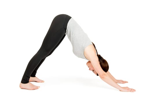 Full-body view of a young black-haired woman looking down on a white background in yoga position (adho muka shavasana)