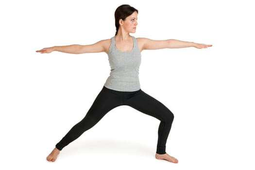 Full-body view of a young black-haired woman during the yogy exercise "the warrior"" (Varabhadrasana) against a white background with slight shadows"