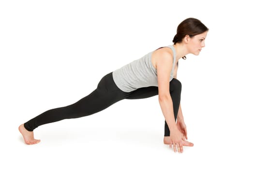Side view of a young woman showing the 4th position (long lunge) of the yoga sun salutation against a white background