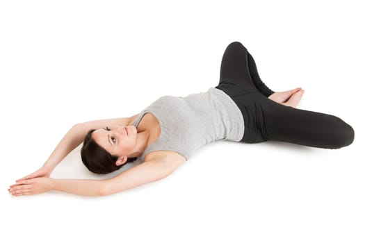 Elevated full-body view of a young woman lying on her back in the yoga position "lying butterfly"" (supta baddha konasana) on a white background."