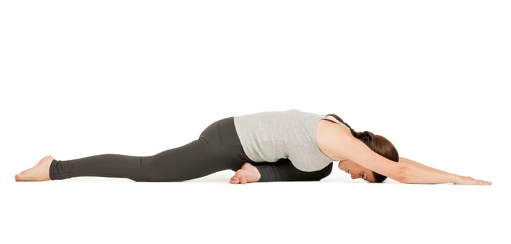 Lateral full-body view of a young woman against a white background showing the yoga exercise the dove (Eka Pada Rajakapotasana).