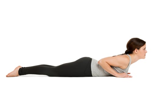 Lateral full-body view of a young woman white background showing the yoga position of the cobra (Bhujangasana) in the basic position.