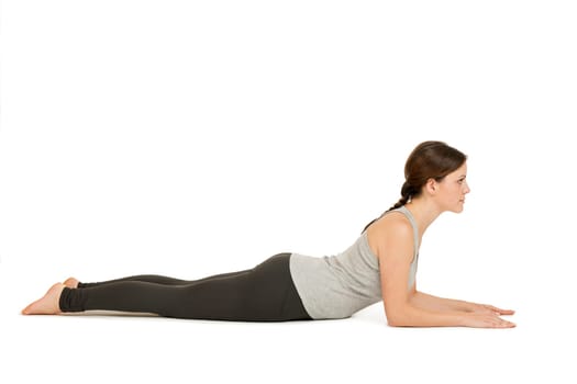 Lateral full-body view of a young woman white background showing the yoga position the Sphinx (Salamba Bhujangasana) in the basic position.
