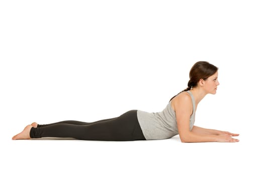 Lateral full-body view of a young woman white background showing the yoga position the Sphinx (Salamba Bhujangasana) in the basic position.