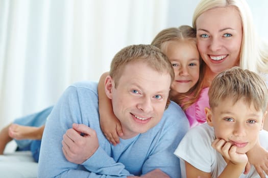 Happy young couple and their children looking at camera
