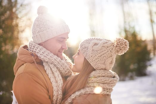 Young amorous couple in winterwear looking at one another outdoors