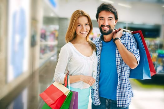 Affectionate shopaholics with paperbags looking at camera