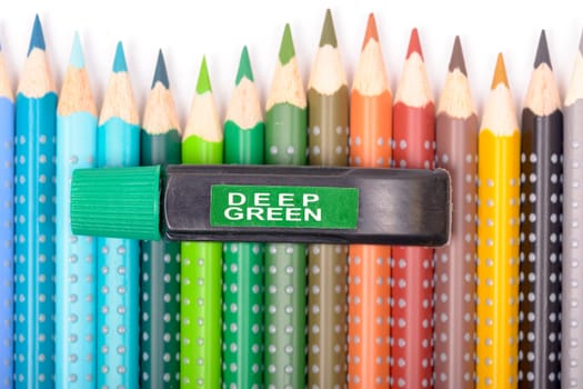 Bundle of colored pencils and tubes of paint on the colorful background