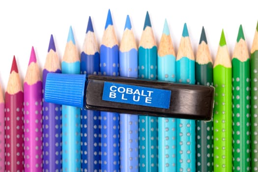 Bundle of colored pencils and tubes of paint on the colorful background
