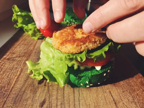 Exotic green burger in a soft bun with sesame seeds tomato onion lettuce cheese and dressing