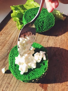 Exotic green burger in a soft bun with sesame seeds tomato onion lettuce cottage cheese