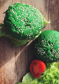 Exotic green burger in a soft bun with sesame seeds tomato onion lettuce cheese and dressing