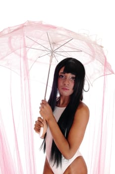 A lovely African American woman standing in a white bathing suit under .pink twill, holding an umbrella, isolated for white background..