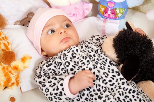 A baby girl surrounded by stuffed animals