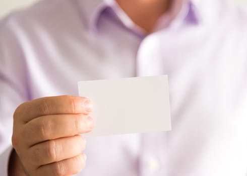 Closeup on businessman holding white empty message card with copy space for text, business concept image with soft focus background