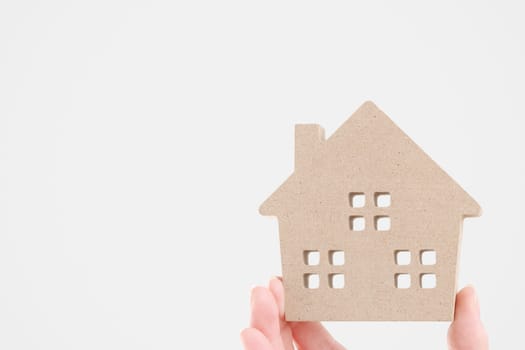 Hand holding miniature model of house on white background