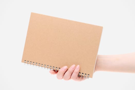 Hand holding blank spiral notebook on white background