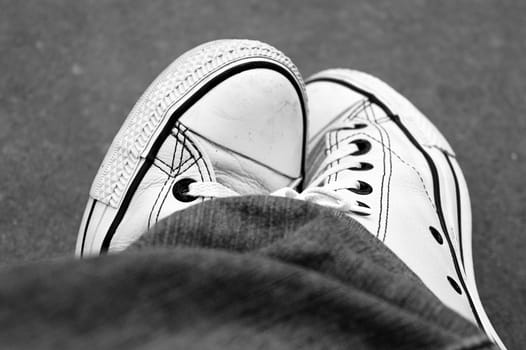 tennis shoes legs crossed black white