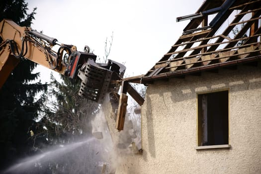 A crane works on the side of a residential building and tears down the walls.