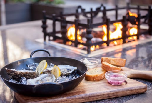 fresh opened oysters on metal black plate fireplace atbackground
