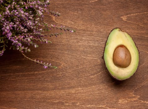one cut avocado on wooden brown background
