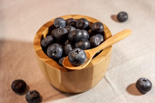 big blueberry in small wooden bowl on textile background