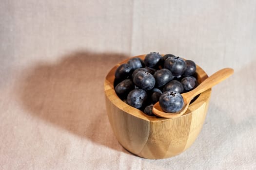 big blueberry in small wooden bowl on textile background