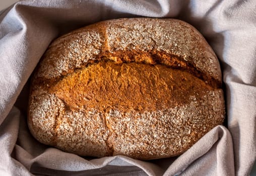 whole wheat loaf of bread wrapped in grey cloth