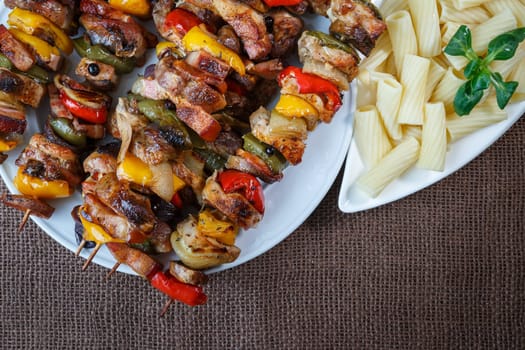Grilled meat skewers - grilled pork kebab with red and yellow pepper on a plate with vegetables