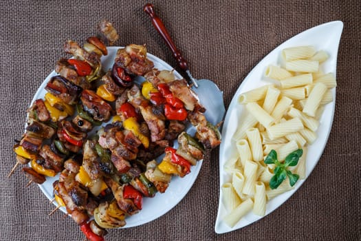 Grilled meat skewers - grilled pork kebab with red and yellow pepper on a plate with vegetables