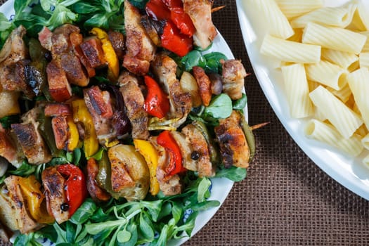 Grilled meat skewers - grilled pork kebab with red and yellow pepper on a plate with vegetables