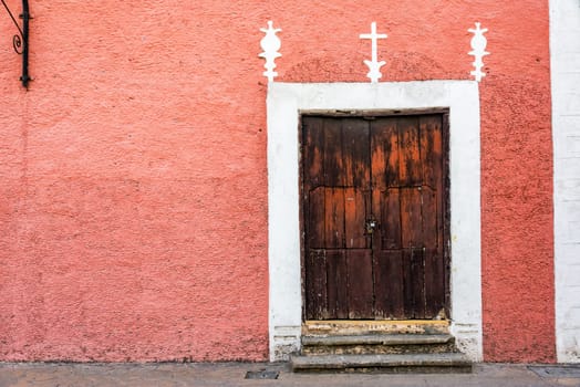 Pink colonial building and rustic wooden door in Valladolid, Mexico