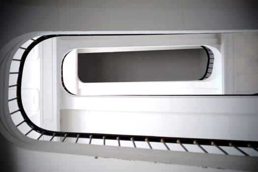 The lower view of a staircase with a spiral staircase and railings.