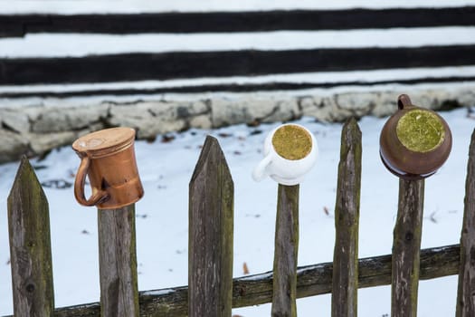 Mugs and pots hanging on the wooden fence
