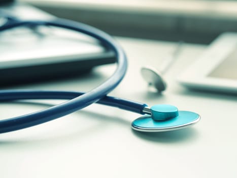 Medical utensils with laptop and tablet computer on a doctor's desk, close up shot with selective focus