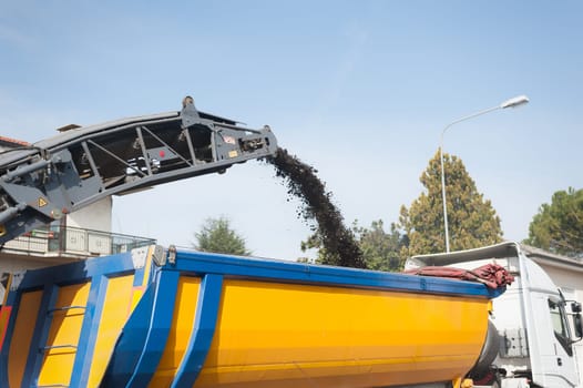 Cold planer machine loading milled asphalt into dump truck.