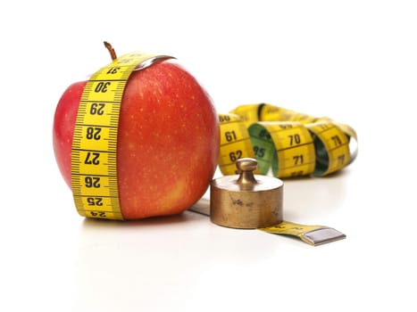 Diet or weight gain concept image with a measuring tape and an apple, isolated on white
