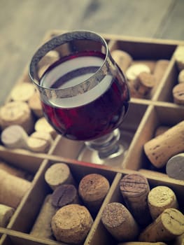 Close up of a glass of red wine with bottle corks, selective focus on the glass
