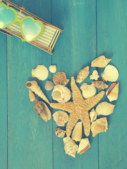 Heart shape of shells and a starfish on a blue vintage wooden background