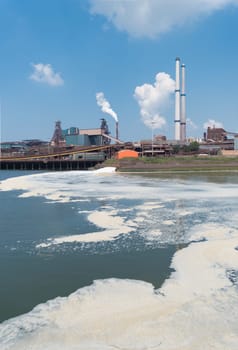 polluted water with a large steel plant in the background