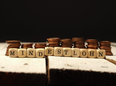 Minimum wage concept with wooden cubes and change as a pile of money