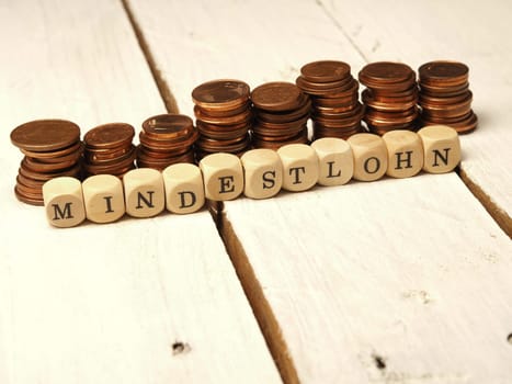 Minimum wage concept with wooden cubes and change as a pile of money