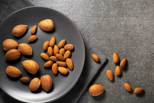 Almonds nuts in their skins and peeled on gray background