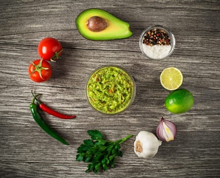 Avocado guacamole with fresh ingredients on wooden table