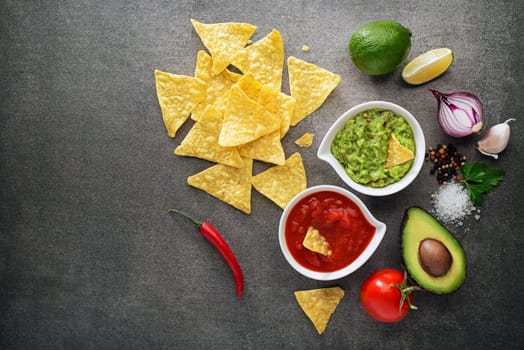 Avocado guacamole and tomato salsa with fresh ingredients on table