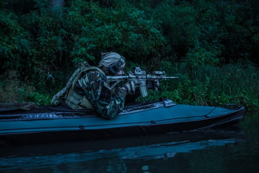 Special forces man with painted face in camouflage uniforms in army kayak. Seeking target, diversionary mission, twilight