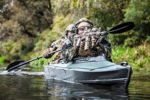 Special forces men with painted faces in camouflage uniforms paddling army kayak. Boat moving across the river, diversionary mission, front view