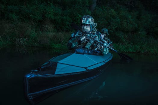 Special forces men with painted faces in camouflage uniforms paddling army kayak. Boat moving calmly across the river, diversionary mission, twilight
