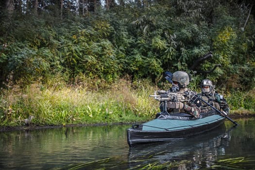 Special forces men with painted faces in camouflage uniforms paddling army kayak. Boat moving across the river, diversionary mission, copy space