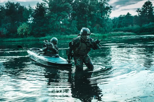 Covert landing. Pair of armed operators with painted faces disembarking from military kayak on river coast. Diversionary mission under cover of darkness